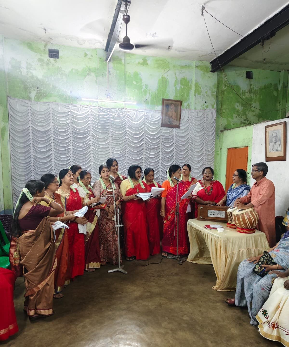Women of the neighbourhood singing together, with harmonium and tabla